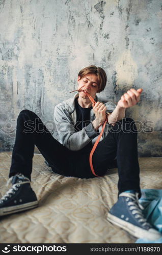 Male druggy with a syringe doing an injection dose in the arm, grunge room interior on background. Narcotic addiction concept, drug addicted people. Male druggy with syringe doing an injection dose