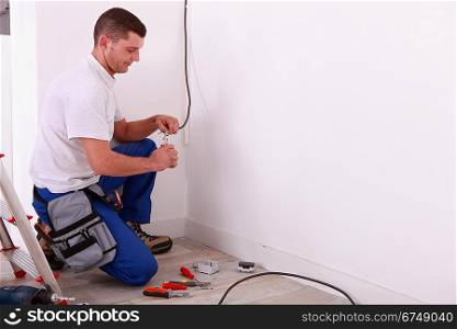 Male electrician preparing length of wire