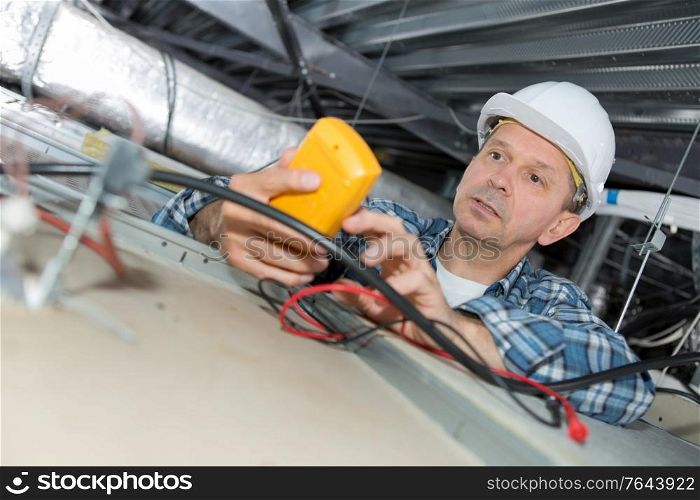 male electrician repairing fire sensor