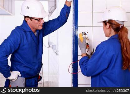 Male electrician supervising female apprentice