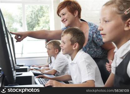 Male Elementary Pupil In Computer Class With Teacher
