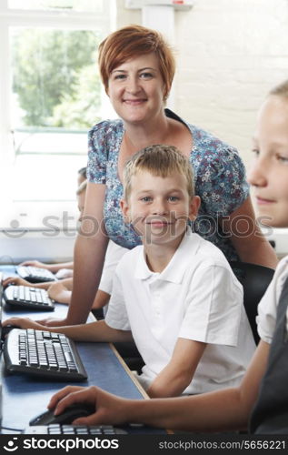 Male Elementary Pupil In Computer Class With Teacher