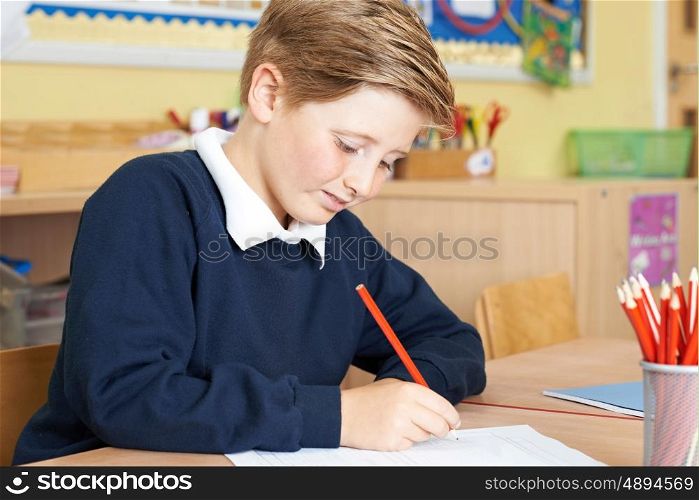 Male Elementary School Pupil Working At Desk