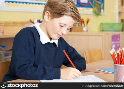 Male Elementary School Pupil Working At Desk