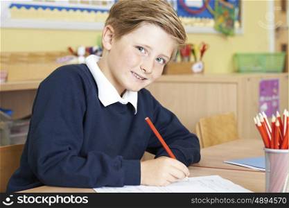 Male Elementary School Pupil Working At Desk