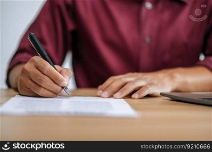 Male employee signing paperwork to approve work at desk