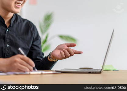 Male employee working in office with laptop and in good mood