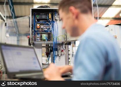 Male Engineer In Factory Using Laptop Computer