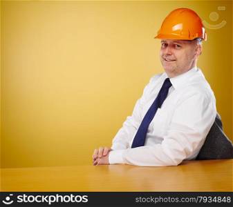 Male engineer in office, he wearing a white shirt and tie, head he wears a orange hard hat