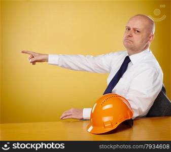 Male engineer in office, he wearing a white shirt and tie, the orange hard hat is on the table