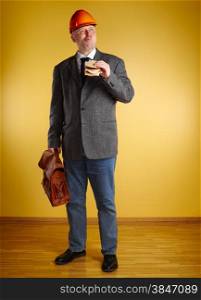 Male engineer in room, he eats sandwich and holds old leather briefcase, parquet floor and yellow wall