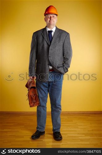 Male engineer, inspect the room and he holds old leather briefcase, parquet floor and yellow wall