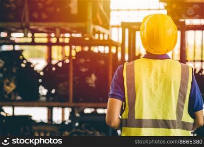 male engineer worker back view looking at shelf in heavy industry factory metal work