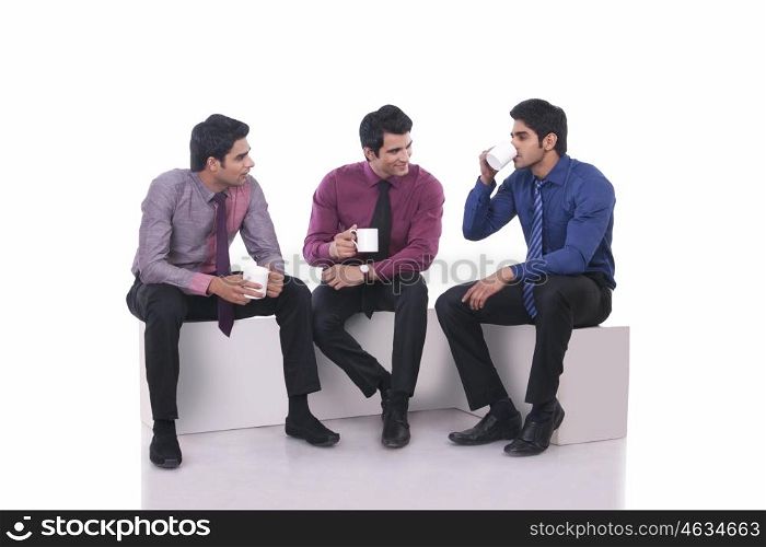 Male executive drinking tea as colleagues watch on