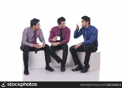 Male executive drinking tea as colleagues watch on