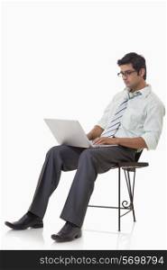 Male executive sitting on chair with laptop