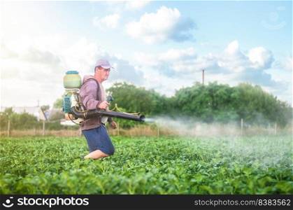 Male farmer with a mist sprayer processes potato bushes with chemicals. Protection of cultivated plants from insects and fungal infections. Control of use of chemicals growing food. Increased harvest.
