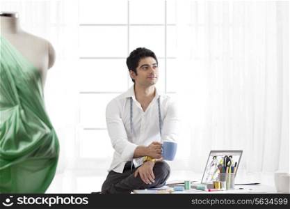 Male fashion designer having coffee while looking away
