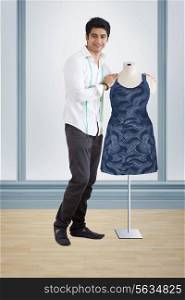 Male fashion designer standing by mannequin