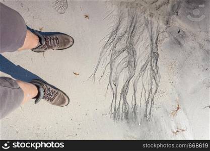 Male feet in hiking shoes on sandy beach. Summertime.. Male feet in hiking shoes on beach