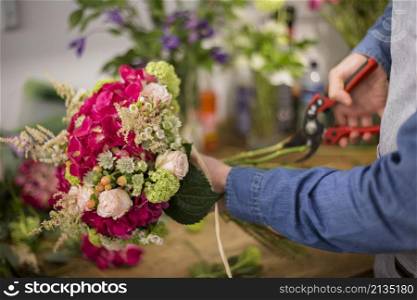 male florist cutting colorful flower bouquet twigs with pruning shears