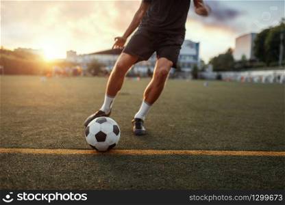 Male football player hits the ball on the field. Footballer on outdoor stadium, workout before competition, soccer training