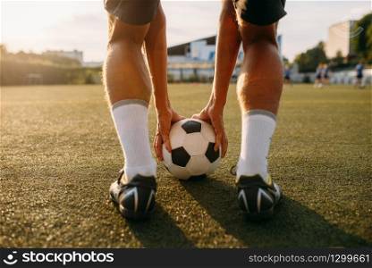 Male football player prepares to hits the ball on the field. Footballer on outdoor stadium at sunny day, workout before game, soccer training