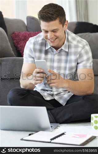 Male Freelance Worker Using Mobile Phone At Home