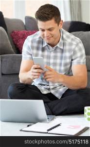 Male Freelance Worker Using Mobile Phone At Home