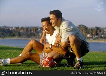 Male Friends Laughing While Playing Soccer In The Park