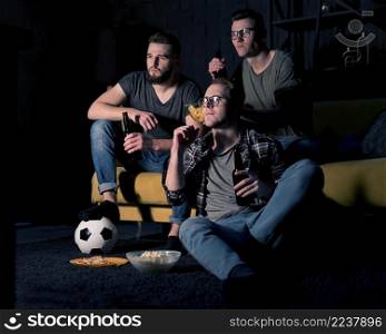 male friends watching sports tv together while having beer snacks
