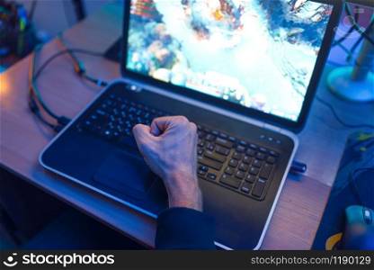 Male gamer fist on laptop keyboard, gaming lifestyle, cybersport. Online multiplayer computer games, consol videogame, player in his room with neon light