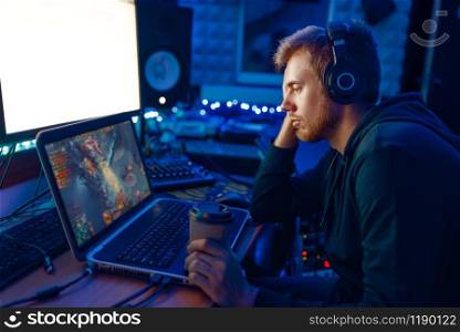 Male gamer with joystick in hands sleeping at his laptop after challenge, gaming lifestyle, cybersport. Online multiplayer computer games, consol videogame, player in his room with neon light. Male gamer sleeping at his laptop after challenge