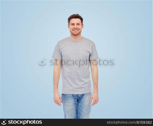 male, gender, fashion and people concept - smiling young man in gray t-shirt and jeans over blue background