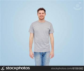 male, gender, fashion and people concept - smiling young man in gray t-shirt and jeans over blue background