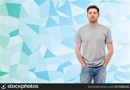 male, gender, fashion and people concept - young man in gray t-shirt and jeans over blue low poly texture background