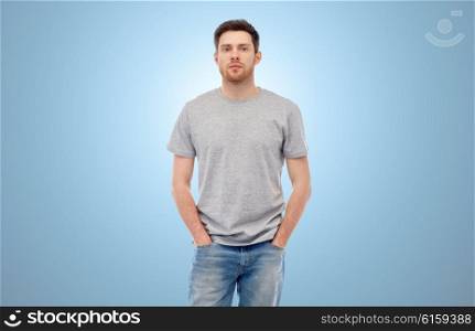 male, gender, fashion and people concept - young man in gray t-shirt and jeans over blue background