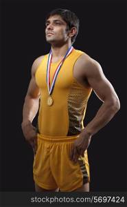 Male gold medalist standing with hands on waist over black background