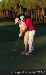 male golf instructor teaching female golf player, personal trainer giving lesson on golf course