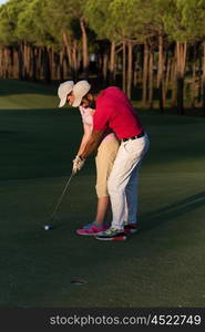 male golf instructor teaching female golf player, personal trainer giving lesson on golf course