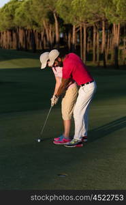 male golf instructor teaching female golf player, personal trainer giving lesson on golf course