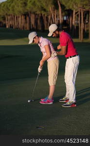 male golf instructor teaching female golf player, personal trainer giving lesson on golf course