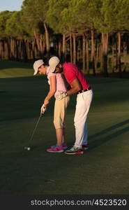 male golf instructor teaching female golf player, personal trainer giving lesson on golf course