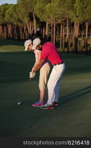 male golf instructor teaching female golf player, personal trainer giving lesson on golf course