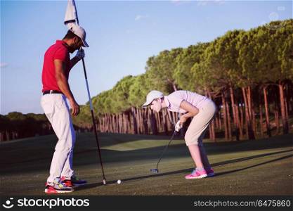 male golf instructor teaching female golf player, personal trainer giving lesson on golf course. golf instructions