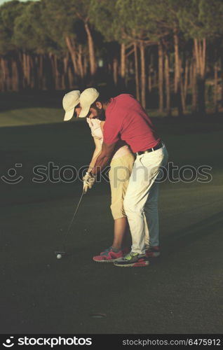 male golf instructor teaching female golf player, personal trainer giving lesson on golf course. golf instructions