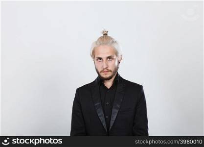 Male hairstyle, elegant fashion concept. Attractive blonde man having hair bun wearing black shirt and jacket looking straight to camera. Attractive blonde man in bun