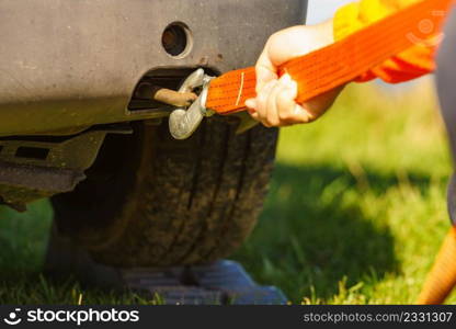 Male hand clings towing rope strap to tow hook in caravan car.. Male hand attaching towline to car