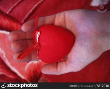 Male hand gives red heart on pink background