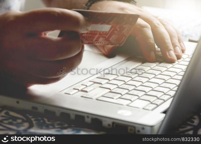 male hand holding a credit card during an internet payment transaction. Concept of e-commerce and online shopping.